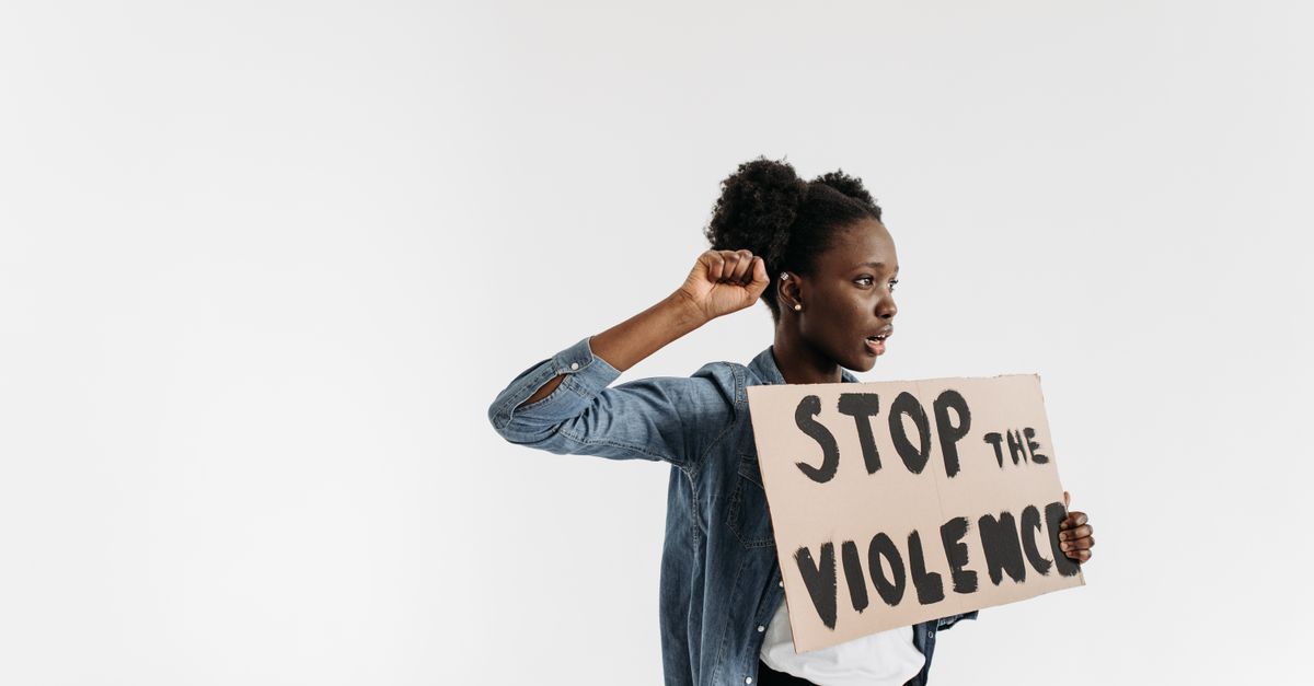 Black woman holding a 'Stop the Violence' sign in a peaceful protest setting.