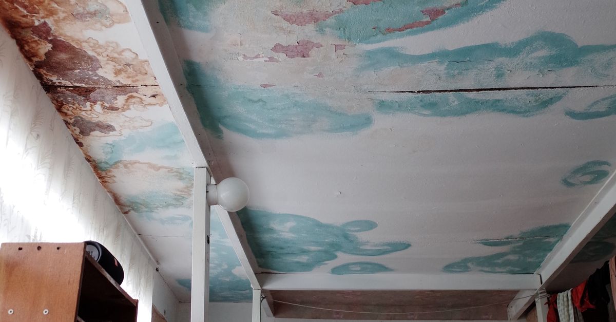 An old bedroom featuring unique ceiling art with peeling paint and vintage furnishings.