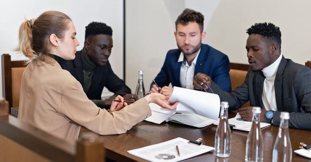 Business team in office meeting discussing contracts with diverse representation.
