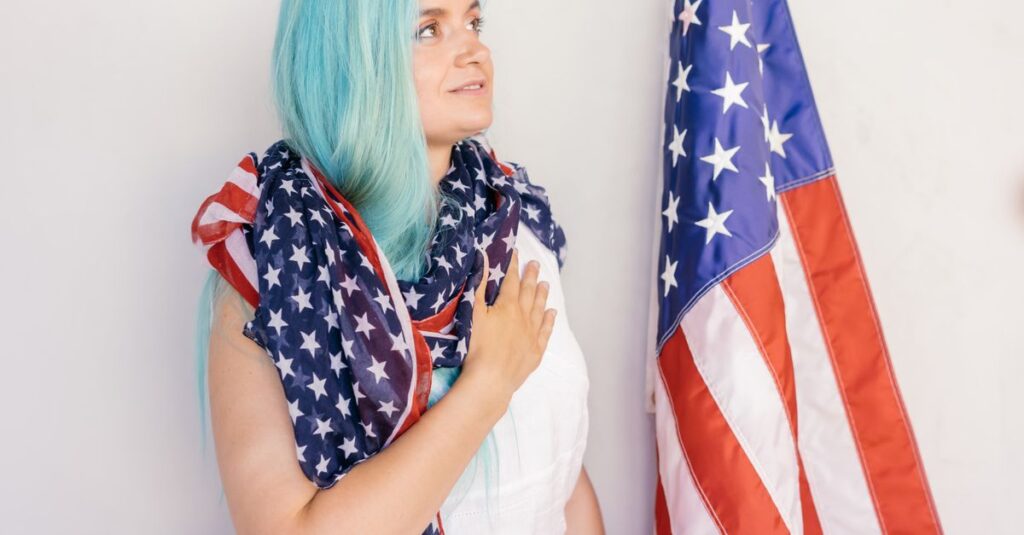 Caucasian woman draped in American flag standing by stars and stripes, showing patriotism.