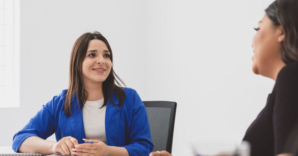 Two women happily engaged in a business meeting in a bright office.
