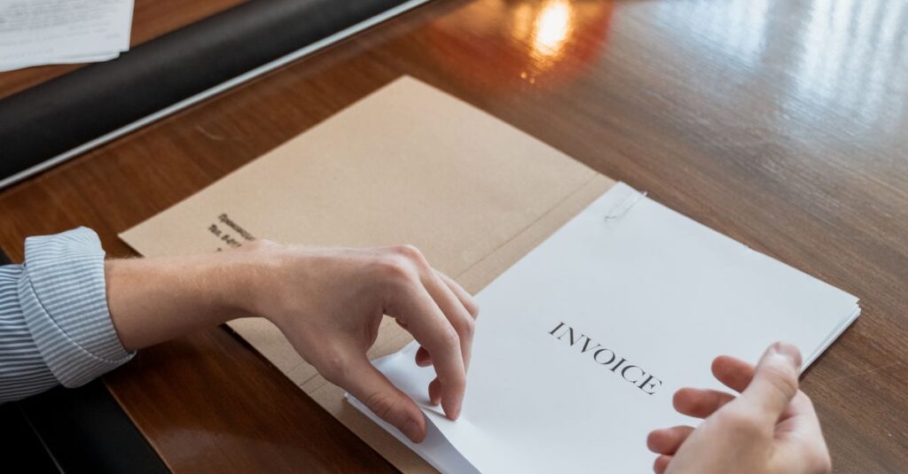 Hands sorting invoices on an office desk, showcasing administrative work indoors.