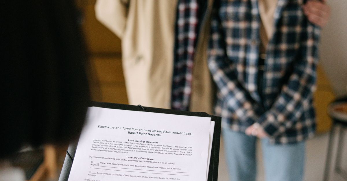 A focused view of a couple discussing a real estate document with an agent in an apartment setting.
