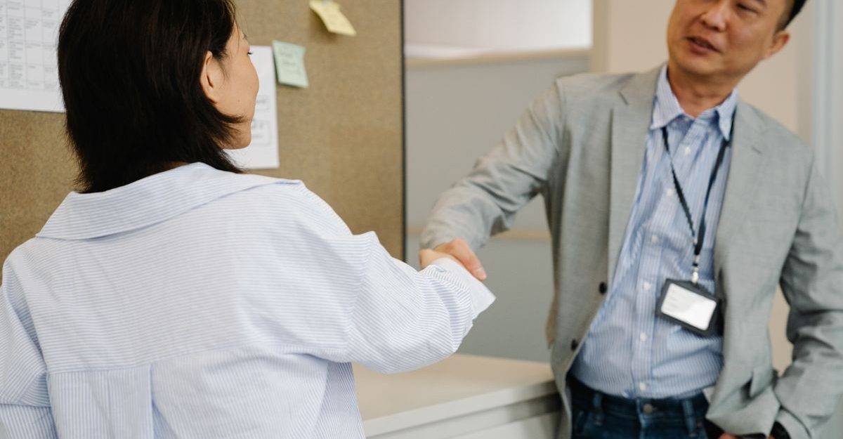 Two professionals engaging in a handshake near an office cubicle, symbolizing agreement.