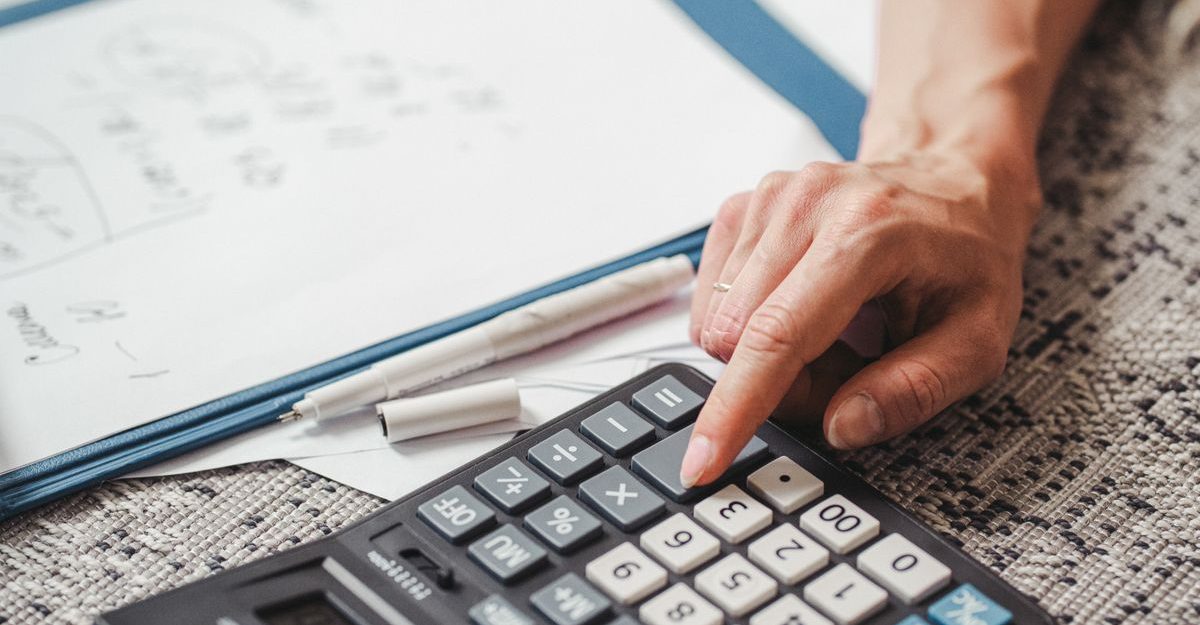 A hand using a calculator on top of documents, indicating financial calculation or analysis.